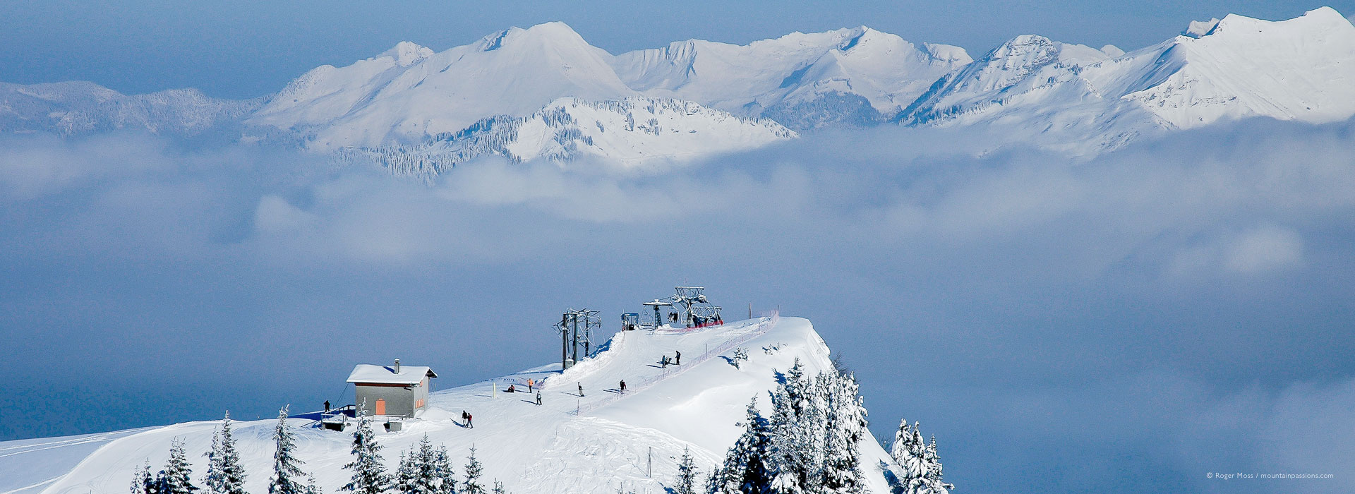 High view of chairlift with skiers, with mountains above clouds at Samoens